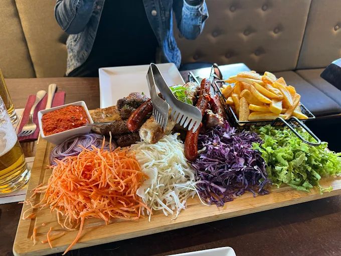 Großes Grillbrett mit Ćevapčići, Würstchen, Pommes und Salaten